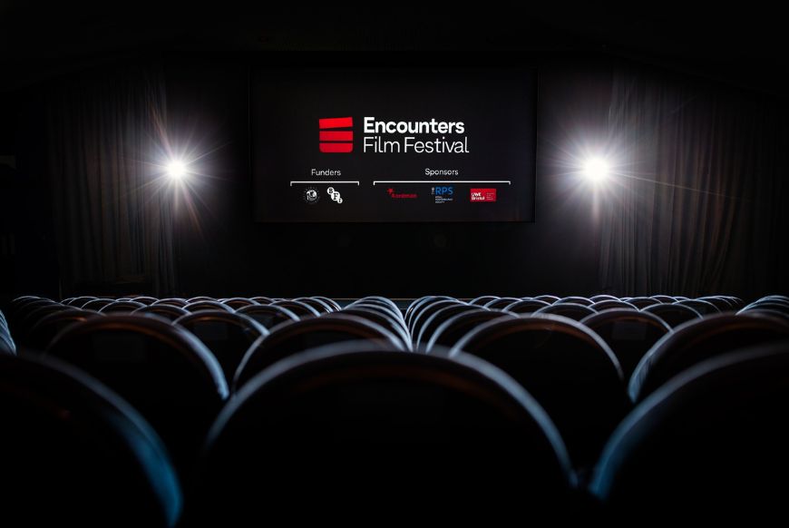 a cinema screen with the logo for the festival, and the backs of lots of cinema seats